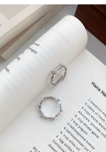 Detailed close-up of S925 sterling silver cross rings with zircon on a book page