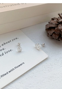 Détail de boucles d'oreilles asymétriques en argent S925 avec fermoirs à vis sur livre