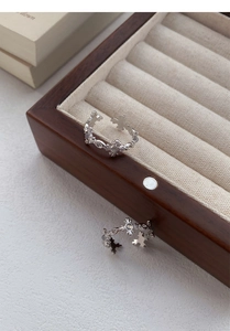 Macro detail of S925 silver cross rings with white agate stones on wooden jewelry box