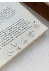 Gros plan de boucles d'oreilles chat en argent S999 sur une page de livre ouverte