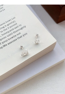 Détail de boucles d'oreilles en argent S999 avec fermoir à vis sur une page de livre