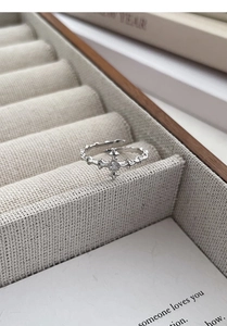 Macro shot of silver cross ring with zircon inlay on a beige jewelry display stand