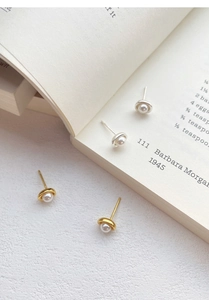 Detaillierte Ansicht der silbernen und goldenen Perlenohrringe auf einem offenen Buch