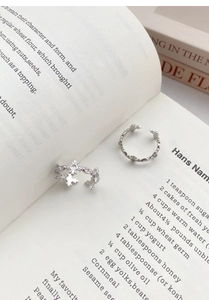 Detailed close-up of S925 silver cross rings with floral relief on vintage book pages