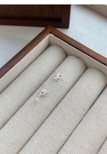 Détail de boucles d'oreilles chat en argent avec yeux noirs sur un coussinet blanc
