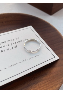 Vista dettagliata dell'anello S999 in argento sterling a treccia su carta minimalista