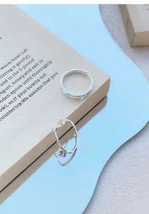 Detailed close-up of a silver jasmine flower ring with woven texture on a book