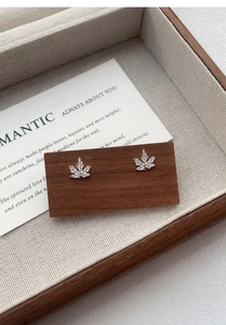 Gros plan de boucles d'oreilles feuille d'érable en argent sur support en bois