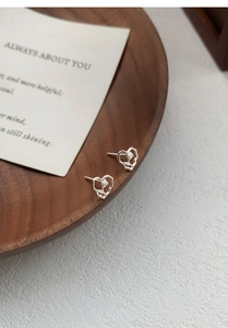 Macro shot of S999 sterling silver heart rose earrings on a stylish wooden tray