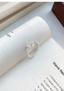 Close-up of S999 sterling silver jasmine flower ring with gold stamen on book page