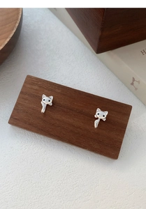 Gros plan détaillé de boucles d'oreilles chat en argent S999 sur un support en bois sombre