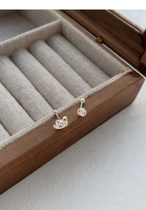 Gros plan de boucles d'oreilles chat porte-bonheur et pièce en argent S999 sur bois