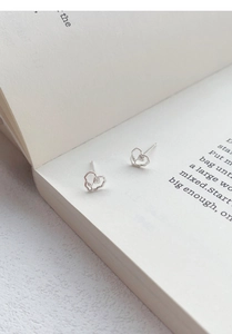 Macro detail of S999 sterling silver heart stud earrings resting on an open book page