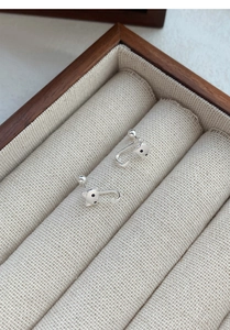 Détail des boucles d'oreilles chat en argent dans un coffret à bijoux en bois