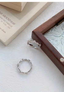 Detailed close-up of retro S925 silver rings with vine and floral patterns on vintage books