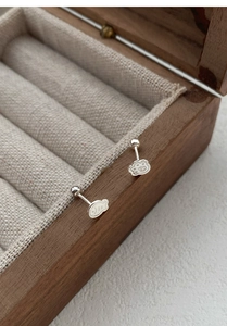 Close-up of S999 sterling silver cat paw and fish stud earrings on a wooden box