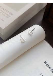 Artistic shot of hollow heart silver earrings resting on a white book's edge
