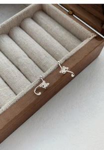 Détail de boucles d'oreilles chat en argent S999 sur un coffret à bijoux en bois