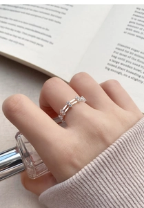 Gros plan d'une bague double en argent S999 avec zircons sur un doigt féminin