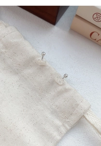 Detailed view of S925 silver cat paw and fish stud earrings on a beige cotton pouch