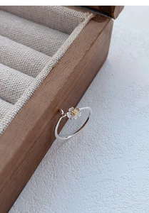 Close-up of S999 silver jasmine flower ring with gold stamen on a dark wooden box