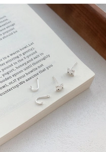 Détail de boucles d'oreilles chat en argent S999 sur un livre au design minimaliste