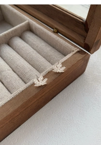 Vue macro détaillée des puces d'oreilles feuille d'érable en argent S999 sur boîte en bois