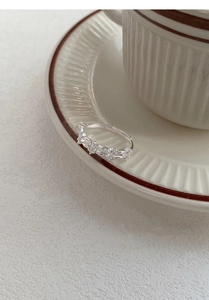 Vue macro d'une bague double en argent avec zircons posée sur le bord d'une tasse blanche