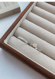 Macro detail of S999 sterling silver jasmine flower rings on a velvet wooden jewelry box
