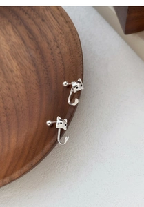 Vue détaillée de boucles d'oreilles chat en argent S999 sur un plateau en bois