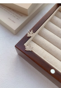 Gros plan de boucles d'oreilles en argent en forme de feuille d'érable sur un coffret