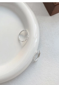 Dettaglio macro degli anelli in argento sterling S999 intrecciati su piatto bianco