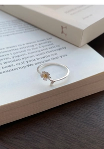 Macro shot of S999 silver jasmine ring with golden flower core on a book page