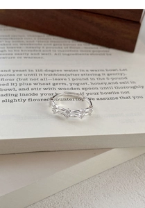Détail d'une bague double en argent avec zircons posée sur une page de livre ancienne