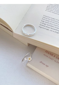 Detailed close-up of S999 silver jasmine flower rings on a vintage book backdrop