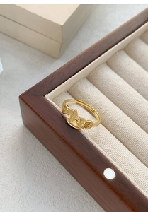 Detailed view of an adjustable golden pig ring with copper coin motifs on a velvet pad