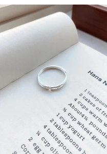 Close-up of S999 sterling silver open ring with hollow jasmine texture on book pages