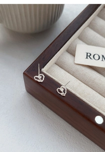 Detailed close-up of S999 sterling silver heart-shaped rose stud earrings on jewelry box