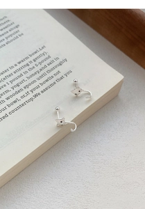 Détail de boucles d'oreilles chat en argent avec longues queues sur un livre ouvert