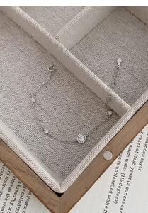Macro shot of S925 sterling silver chain bracelet with halo zircon pendants on linen tray