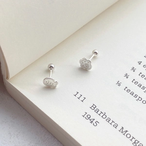 S925 sterling silver cat paw and fish stud earrings on a vintage book page
