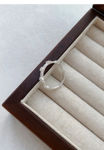 Vue macro d'une bague double en argent S999 avec zircons dans un écrin en bois chic