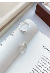 Artistic detail of S999 silver jasmine rings on open book with floral and textured patterns