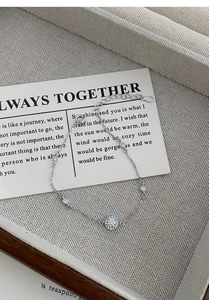Close-up of S999 silver bracelet with sparkling zircon charms on beige jewelry tray