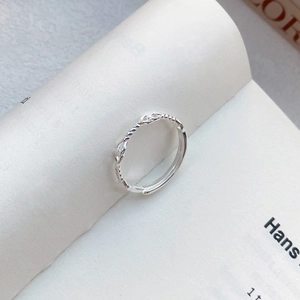 Anello in argento S999 a corda intrecciata su libro aperto con luce soffusa