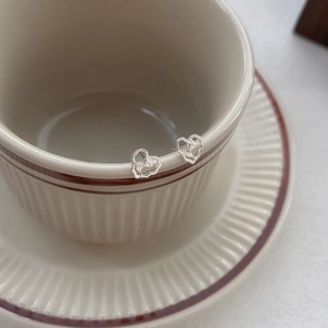 Elegant S999 silver hollow heart earrings with delicate tulip flower details on a beige cup