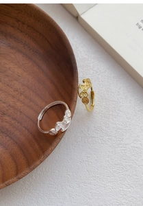 Close-up of gold and silver open rings with hollow bear and coin designs on wood