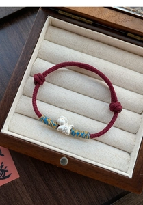 Detailed shot of S999 silver horse charm on a hand-woven red cord bracelet with adjust knot