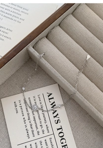Close-up of S999 silver bracelet with halo zircon pendant on a beige linen display