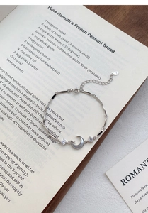 Detailed view of S999 silver moon and star bracelet with S925 hallmark on open book